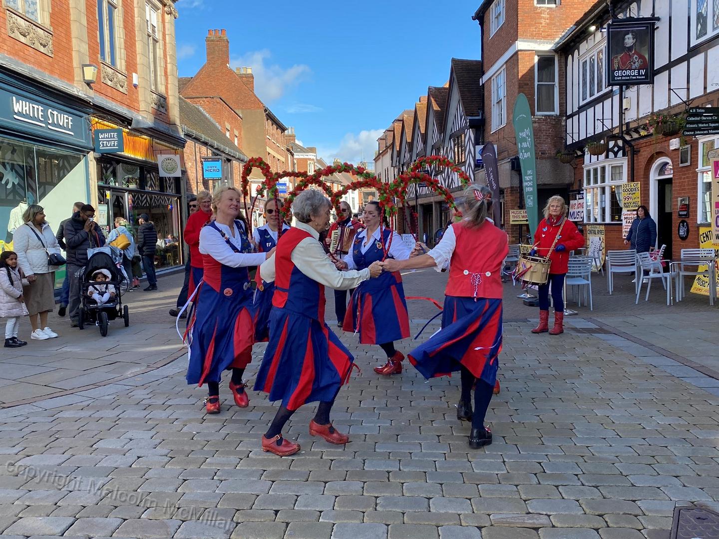 dancing in a circle on a traditional stone set street